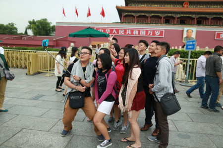 Tourists from Malaysia take a photo using a selfie stick in front of the Tian'anmen Rostrum in Beijing in September. (Photo: China Daily/Zhu Xingxin)  