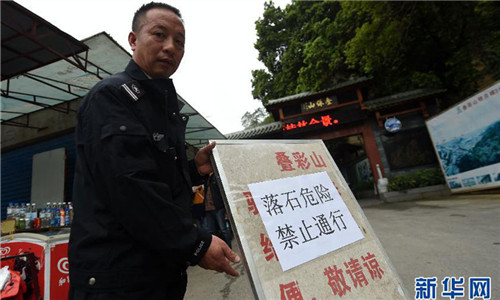 A security guard holds a board to warn visitors of falling boulders in the Decai Mountain scenic area in South China's Guilin city, Guangxi Zhuang Autonomous Region on March 19, 2015. (Photo/Xinhua)