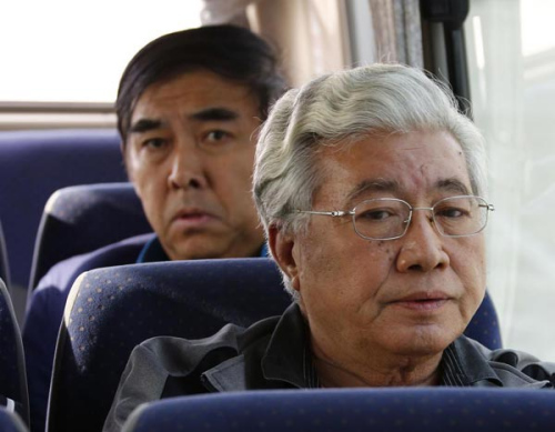 Pang Shunxi, back, a former tax official of Tianjin municipality, and An Huimin, former general manager of a trade company in Tianjin, are escorted back to Beijing, March 28, 2015, after three months of exile in Laos. (Photo/Xinhua)