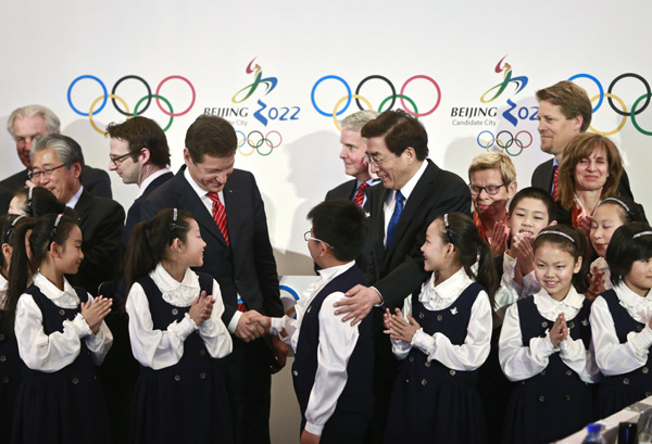 Alexander Zhukov (center left), chairman of the International Olympic Committee's evaluation commission, and Guo Jinlong, Party chief of Beijing, greet a primary school student after a wrap-up news conference for the commission's inspection visit to Beijing on Saturday. FENG YONGBIN/CHINA DAILY