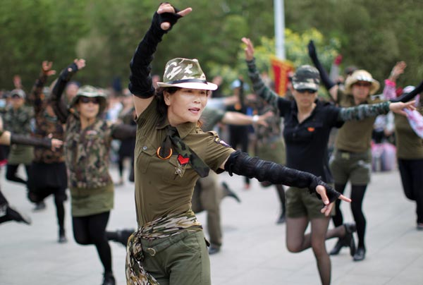Dancers at a park in Beijing wear clothes inspired by military uniforms. Square dancers attract crowds of spectators by wearing colorful costumes and choreographing their own steps. (Photo: Zou Hong/China Daily)  