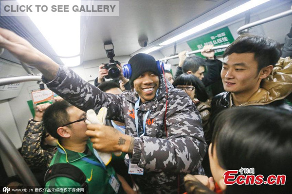 Former NBA star Stephon Marbury is surrounded by fans on a subway train in Beijing on December 8, 2014. Serving as a volunteer, Marbury was on the train to clean illegal adlets. [Photo/ CFP]