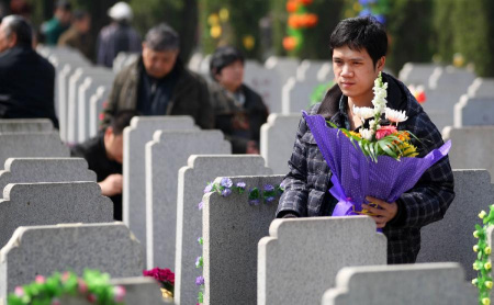 A man holds a bunch of flowers to pay homage to the deceased at a cemetery on the Qingming Festival in Nantong, east China's Jiangsu Province, April 4, 2013. (Xinhua/Xu Peiqin) 