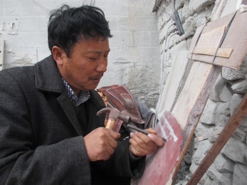 Olo Tsering carves mantras in his workshop, a skill he describes as a valuable gift from his ancestors.(Photo: Palden Nyima/China Daily)