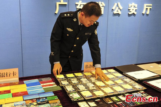 A policeman shows items confiscated from busting an online gambling ring in Guangzhou, South China's Guangdong province, April 1, 2015. Guangdong police detained 1,071 suspects and froze bets valued at 330 million yuan (US$52.8 million), the largest such series of arrests since the founding of Peoples Republic of China in 1949. (Photo: China News Service/Chen Jimin)