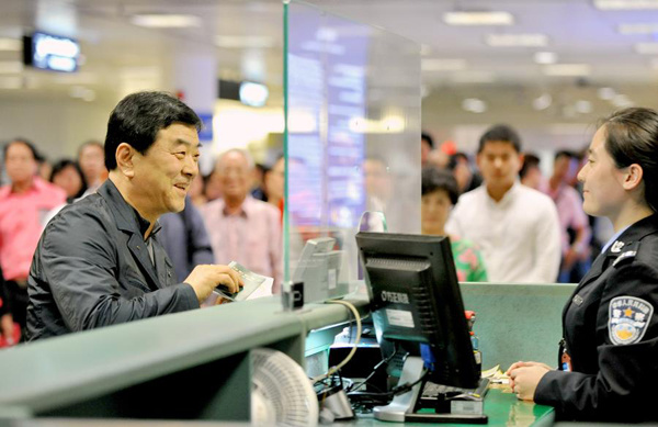 A passenger from South Korea (L) have his passport checked in Xiamen,southeast China's Fujian province, April 2, 2015. The first group of passengers with a 72-hour visa-free stay in Xiamen reached Xiamen Gaoqi International Airport Thursday. Xiamen started to allow 72-hour transit visa exemptions for foreign nationals from 51 countries and regions from Wednesday.(Photo/Xinhua)