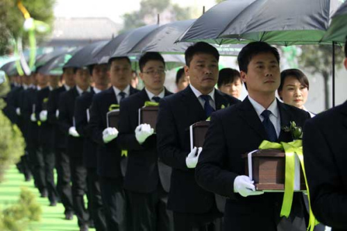 Employees of a funeral home hold cremation caskets at a funeral in Henan in March. (China Daily/Niu Yuan)