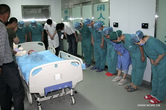 Medical workers bowed to Feng Junxi, the little girl whose parents donated her organs after her death in Beijing, June 9, 2012. [Photo/Xinhua]