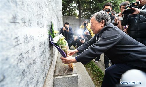 Survivor of Nanjing Massacre Xia Shuqin lays flowers in front of a wall inscribed the name list of victims at the Memorial Hall of the Victims in Nanjing Massacre by Japanese Invaders on the Qingming Festival in Nanjing, capital of east China's Jiangsu Province, April 5, 2015. Photo: Xinhua