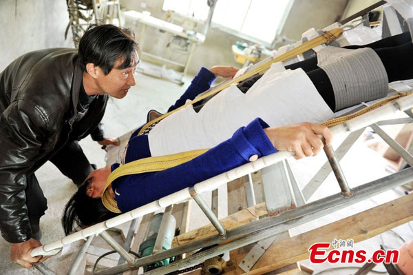 Zhu Qinghua manipulates the stone removing bed to keep his wife in an upside-down position. (Photo/CFP)