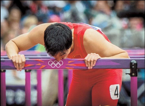 Liu kisses his hurdle after falling in a 110m hurdles heat at the London 2012 Olympic Games, on Aug 7, 2012.(Photo/Shanghai Daily )