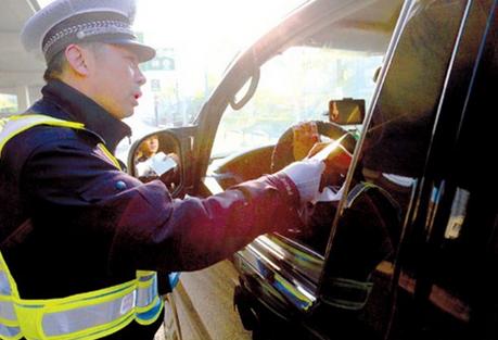 A traffic police officer helps the driver of a vehicle with an out-of-town plate to find an alternative route through the city yesterday. Cars with non-local plates are now banned from the citys highways for an extended period as Shanghai authorities seek to resolve a growing congestion problem. (Photo: Shanghai Daily/Yong Kai)