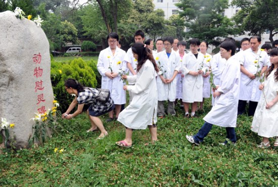 Students at Xi'an Jiaotong University's Health Sciences Center leave flowers at a monument for lab animals. (Photo/China Daily)
