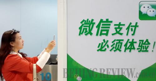 SHOPPING: A Beijing resident makes payment for a drink from a vending machine through WeChat at a Beijing subway station (LI XIN)