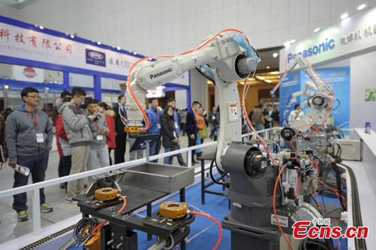Visitors look intelligent robot demonstrating operation at the 11th China (Tianjin) International Equipment and Manufacturing Expo in Tianjin, March 12, 2015. The expo, covers an area of 80,000 square meters, is the largest robot show in China. China is now the world's largest industrial robot market with over 30 robot factories under construction, Xinhua reported in 2014. (Photo: China News Service/Tong Yu)