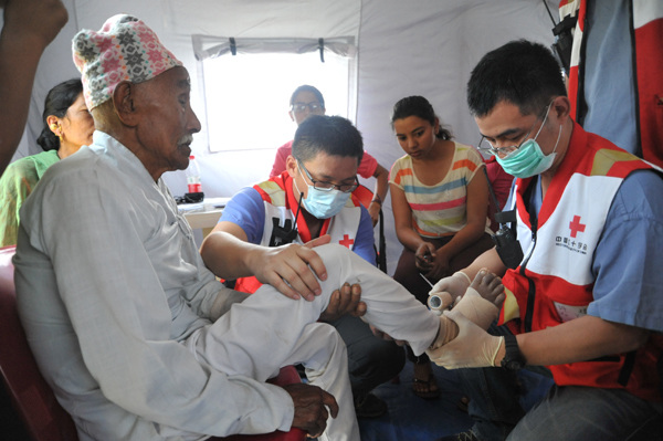 Doctors from the Chinese Red Cross team attend to an elderly resident's broken leg in Magagun, Nepal, on May 6, 2015. Provided to China Daily  