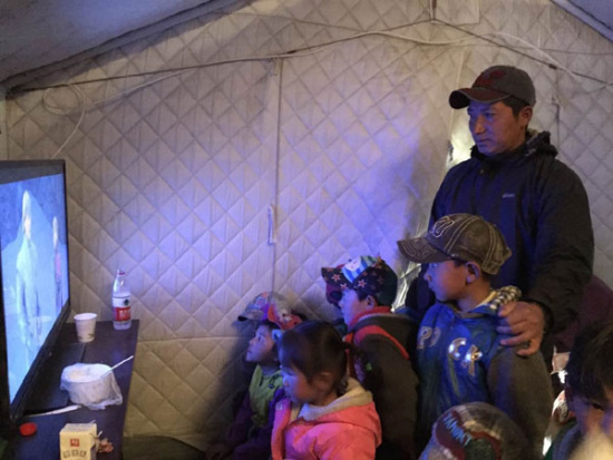 Tsetan Dorje rests a hand on the shoulder of his son Tenzin Tsering at a tent kindergarten in Lhaze county. Provided to China Daily