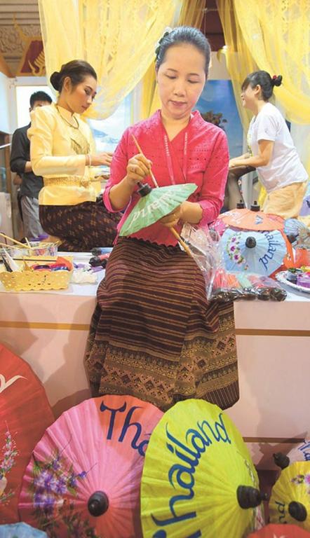 A woman paints parasols at a stand to promote Thai tourism yesterday at the Shanghai World Travel Fair. The event runs through Sunday. (Photo: Shanghai Daily/Wang Rongjiang)