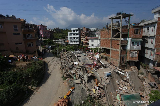Rescuers search for victims below the debris of a damaged building in Kathmandu, Nepal, May 14, 2015. The death toll in a fresh powerful quake that hit Nepal on Tuesday has climbed to 96 and around 2563 others injured, Nepal Police said in its latest update on Thursday. (Xinhua/Sunil Sharma)