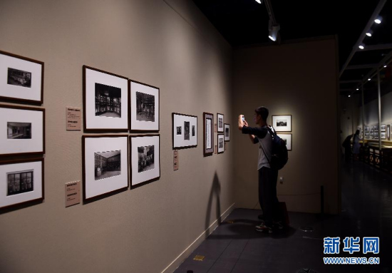 A visitor takes pictures of old photos on an exhibit held by the Palace Museum on May 17, 2015. (Photo: Xinhua/Jin Liangkuai)