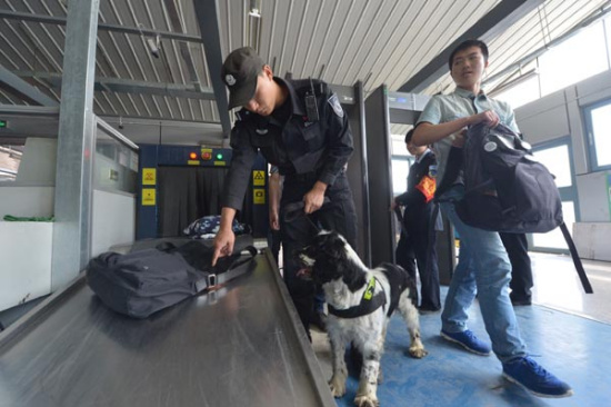 A police officer instructs a sniffer dog to check a bag during a subway security check in Beijing thismonth. (Liu Chang/For China Daily)