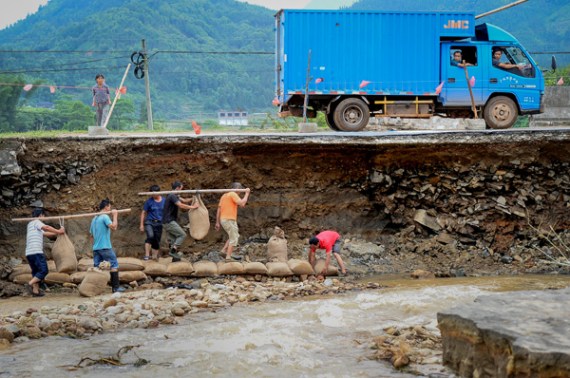 Residents repair a road damaged by flooding in Sanfang, a township in Liuzhou, Guangxi Zhuang autonomous region, on Saturday after the region was hit by heavy rain. Provided to China Daily