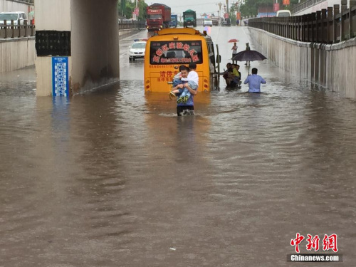 A police officer has two children in his arms. (Photo: China News Service/Zhong Xin)