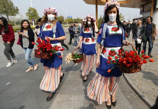 Performers hand out tulips to passersby in an attempt to improve public awareness about environmental protection in Nanjing, Jiangsu province, in March. (Yang Bo/China News Service)