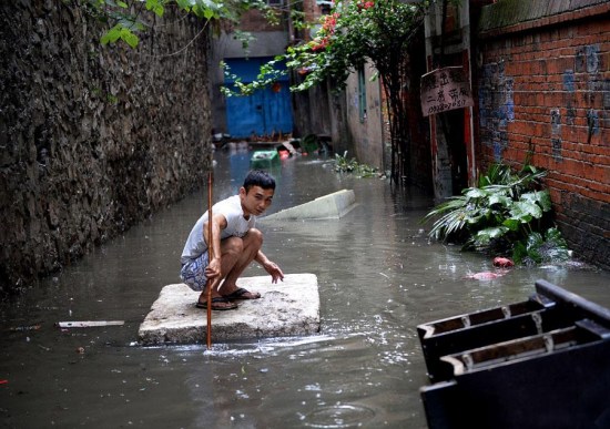 A man balances on a foam raft after heavy rain hit the southwestern province of Guangxi on Wednesday. More downpours are expected in South China during the coming days. (Photo/Asianewsphoto)