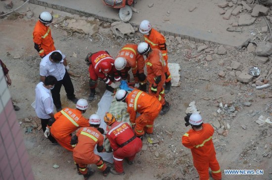 Rescuers transfer a victim's body in Guiyang, capital of southwest China's Guizhou Province, May 21, 2015. Five bodies were found in the rubble of a collapsed building in central Guiyang Thursday. The accident happened on Wednesday, when the nine-story building with 114 residents living in it fell down. (Xinhua/Ou Dongqu)