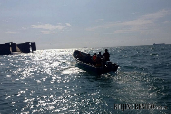 Rescuers search for people on the capsized sand carrier. (Photo/Beijing Review)