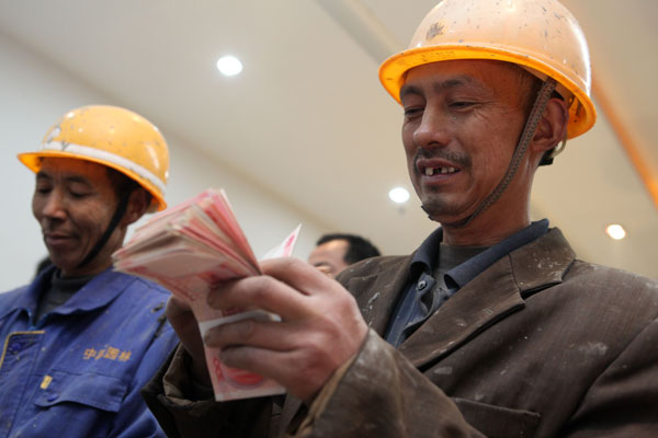 Migrant workers receive their pay at a construction site in Dazu district, Chongqing, on Dec 26, 2013. (Photo/China Daily)