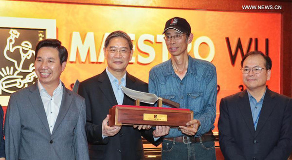 Zhang Zhijun (2nd L), director of the State Council Taiwan Affairs Office, receives a steel knife presented by a local entrepreneur in Kinmen, southeast Taiwan, on May 24, 2015. Zhang arrived on the island of Kinmen, which is two kilometers from the coastal mainland city of Xiamen, on Saturday for a two-day visit. (Photo: Xinhua/Cai Yang)