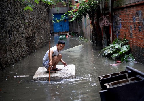A man balances on a foam raft after heavy rain hit the southwestern province of Guangxi on Wednesday. More downpours are expected in South China during the coming days. (Photo/Asianewsphoto)