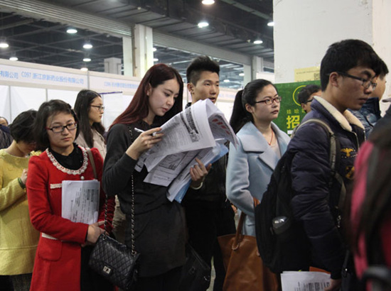 Job seekers hand in their resumes at a job fair in Hangzhou on Tuesday, March 17, 2015. A newly released report said graduates from domestic colleges are being favored over those who studied overseas. Hu Yuanyong / For China Daily