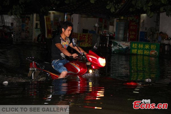 A motorcyclist wades through a flooded street after heavy rain in Liuzhou city, Southwest China's Guangxi Zhuang autonomous region, May 19, 2015. Guangxi declared an emergency on Tuesday as it was hit by a new round of torrential rain. (Photo: China News Service/Zhu Liurong)
