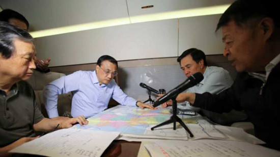Premier Li listens to the report of the accident on the plane flying to the site on Tuesday. (Photo provided for China Daily)