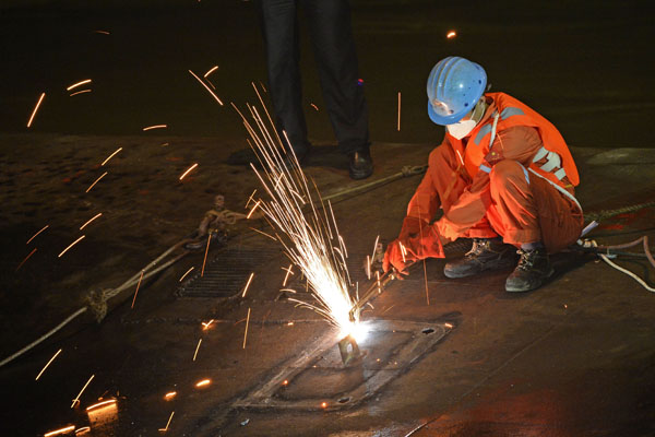 With the hope of finding more survivors, a rescue worker starts to cut a hole in the bottom of the capsized Eastern Star in the Jianli section of the Yangtze River in Hubei province on Wednesday. (Photo by LI XI / HUBEI DAILY)