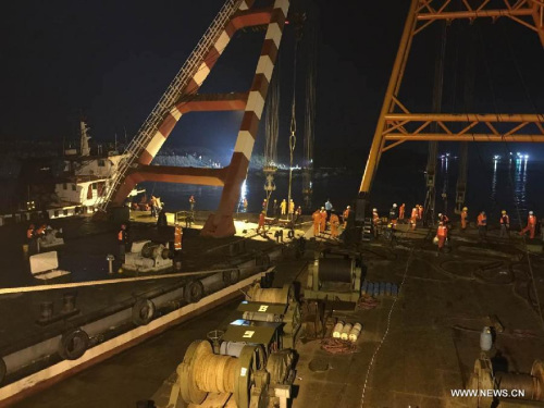 The photo taken by a cell phone shows the search and rescue team starting to right the capsized cruise ship Eastern Star in the section of Jianli on the Yangtze River, central China's Hubei Province, June 4, 2015. The ship will be hoisted by cranes on site capable of lifting the whole vessel and set it upright. (Xinhua/Sun Chengyu)