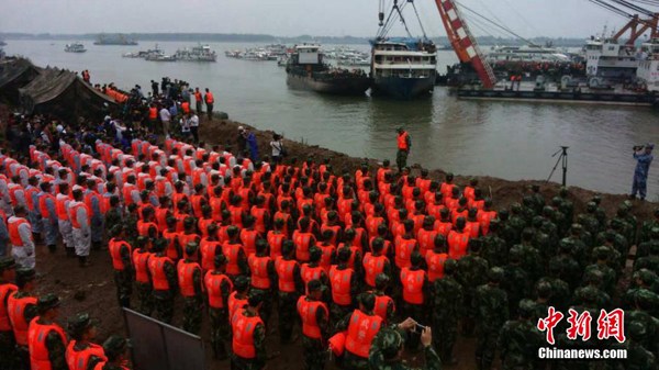 Hundreds of rescue workers stand towards the battered boat during a three-minute silent tribute to the victims at around 9 a.m. on Sunday, June 7, 2015. (Photo/China News Service)