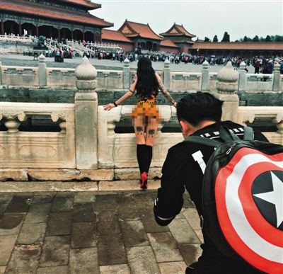 The photographer shoots a scantily-clad model with tourists nearby. [Photo/Weibo] 