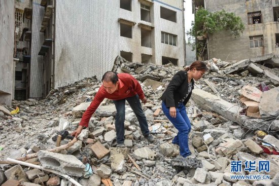 Ji Yuankui (L) and Luo Kaisu (R) looks for items among debris on June 11.(Photo: Xinhua/Liu Xu)