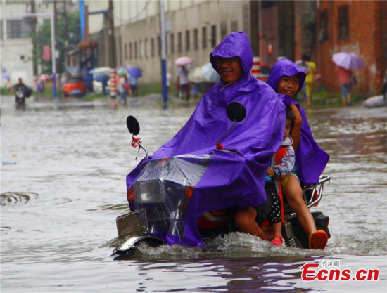 A motorcyclist braves floods to deliver a student to school on a street in Liuzhou city, Southwest Chinas Guangxi Zhuang autonomous region, June 11, 2015.(Photo: China News Service/Zhu Liurong) 
