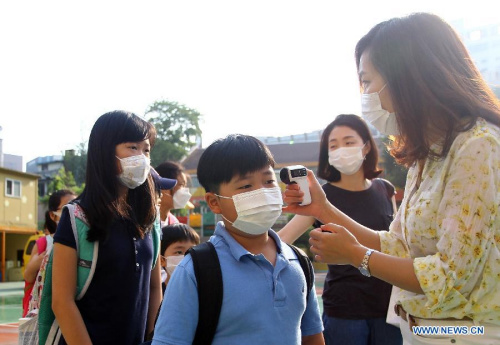 A teacher checks the body temperature of students in an elementary school in Seoul, South Korea, on June 11, 2015. A total of 2,431 schools in South Korea have closed due to the outbreak of Middle East Respiratory Syndrome (MERS). (Xinhua/Yao Qilin)