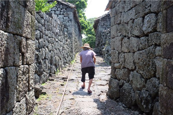 An old woman walks in an alley paved with lava stones in Sanqing village in Haikou, South China's Hainan province, on June 9, 2015. (Photo by Huang Yiming/China Daily)