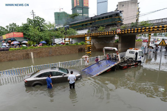 People transfer a flooded car in Liuzhou City, south China's Guangxi Zhuang Autonomous Region, June 14, 2015. The National Meteorological Center (NMC) issued a yellow alert for rainstorms in southern China on Sunday. (Photo: Xinhua/Li Hanchi) 