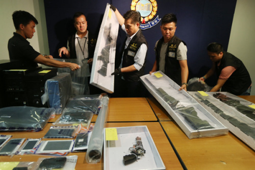 Police officers at a news conference, held on June 15, arrange air rifles seized with explosives in Hong Kong. Police in Hong Kong arrested nine people in raids and seized suspected contraband, authorities said. (Roy Liu/China Daily)