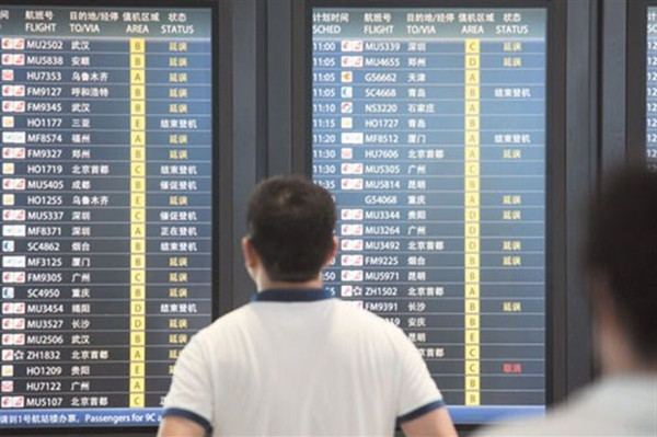 A man checks flight information on an electric board at Shanghai Pudong International Airport yesterday. The heavy downpour led to the cancellation of about 200 flights. (CNS photo)