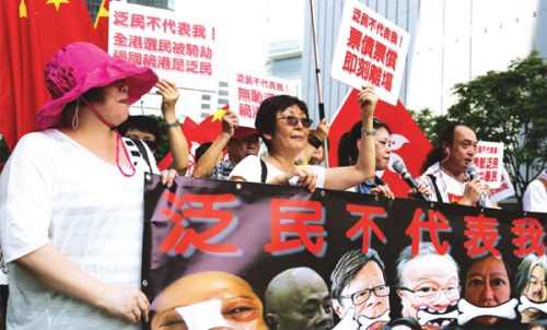 Residents wave banners condemning the opposition during a rally in support of the electoral reform package outside the Central Government Offices on Thursday. (phototo Parker Zheng/China Daily)