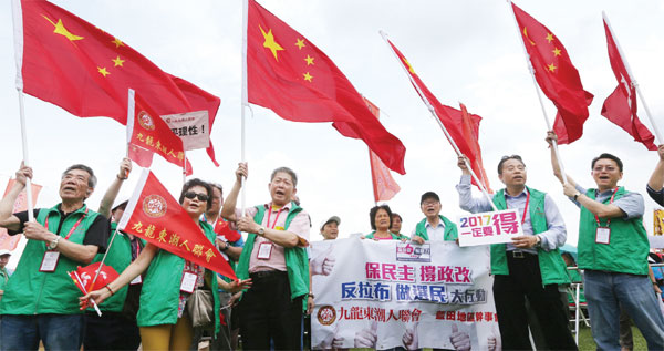 Residents of Kowloon East wave national flags and shout slogans in support for the electoral reform package at a rally in Tamar Park on June 6, 2015. (Parker Zheng / China Daily)